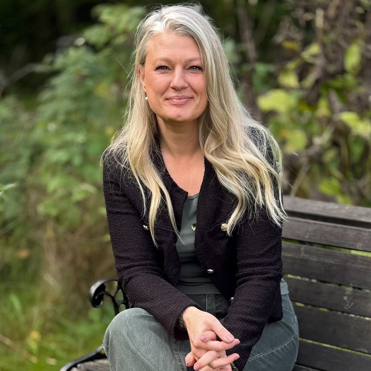 Ann-Sofie Nørby sidder på en havebænk og smiler